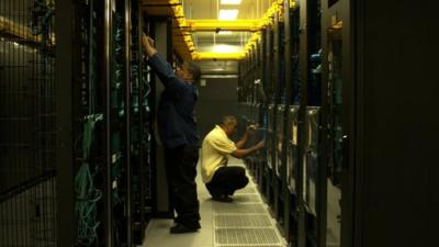 Two men work with computer servers