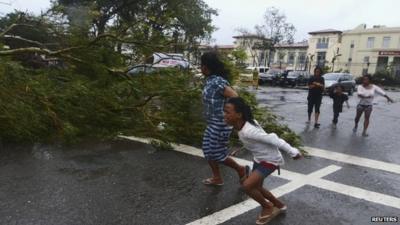 Residents rush to safety past a fallen tree during strong winds brought by Typhoon Haiyan that hit Cebu city