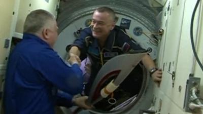 Expedition 37 commander Fyodor Yurchikhin (L) shakes hands with Expedition 38 cosmonaut Mikhail Tyurin after Tyurin handed over the Olympic torch