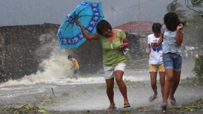 Locals walk in strong winds from Typhoon Haiyan