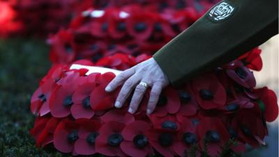 Solider places his hand on wreath