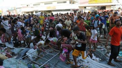 Residents watch as others throw looted goods from a warehouse in the town of Guiuan, Eastern Samar province in the central Philippines