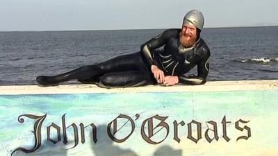 Sean Conway lies on wall painted with the name John O'Groats