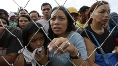 Residents queue up to receive treatment and relief supplies at Tacloban airport Monday