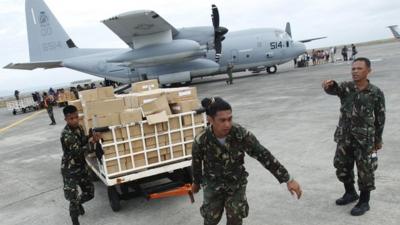 Military personnel deliver aid supplies which arrived in Tacloban