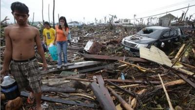 Survivors walk along debris from damaged homes at typhoon ravaged Tacloban