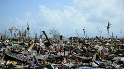 A woman stands amid the debris in Tacloban