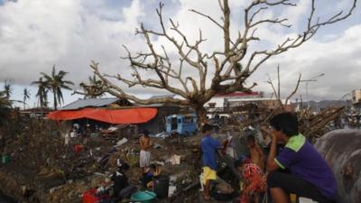 People bathe using water from a broken water pipe along a street canal, after super typhoon Haiyan battered Tacloban City