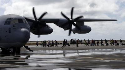 Expatriates typhoon survivors board a U.S. military transport plane Wednesday Nov. 13, 2013 from the damaged Tacloban airport at Tacloban city, Leyte province in central Philippines