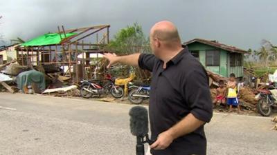 Alastair Leithead in front of damaged buildings