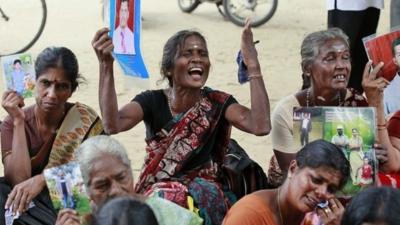 Sri Lankan ethnic Tamil women cry holding portraits of their missing relatives during a protest in Jaffna, Sri Lanka, Friday, Nov. 15, 2013.