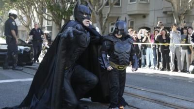 Miles Scott, dressed as Batkid, right, walks with Batman before saving a damsel in distress in San Francisco, Friday, Nov. 15, 2013