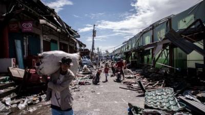 People make their way past shops destroyed by Typhoon Haiyan in Tanauan, on the eastern island of Leyte