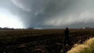 Man in field photographing tornado