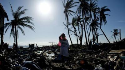 Boy standing among debris of homes in Tacloban, Philippines, after Typhoon Haiyan