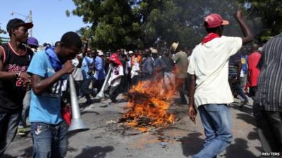 Protesters circle a burning road block