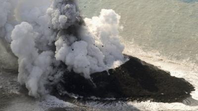 Island with smoke and lava spewing out of it