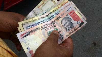 A man counts Indian rupee notes