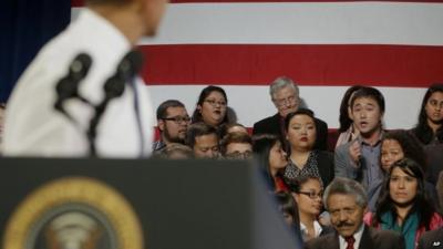 President Barack Obama, left, stops and turns around to responds to an unidentified man who heckled him about anti-deportation policies, 25 November 2013