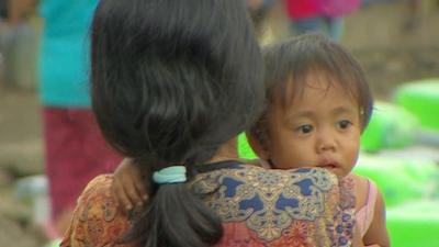 Mother carries child amidst typhoon Haiyan debris