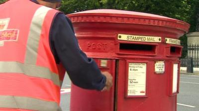 Postman collects letters from a post box