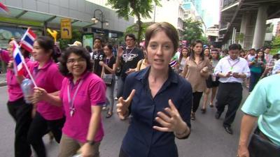 The BBC's Lucy Williamson walks amongst a protest in Bangkok