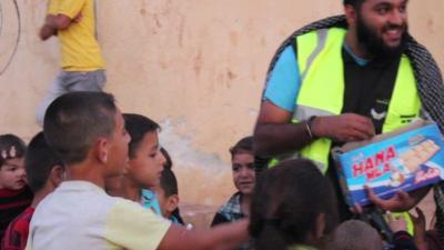 British man giving sweets to Syrian children