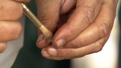 A hand holding a small fossil