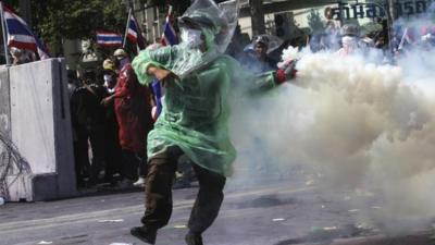 An anti-government protester throws back a teargas canister towards police during clashes near the metropolitan police headquarters in Bangkok December 2, 2013