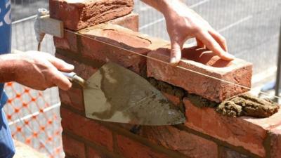 A brick layer builds an extension.