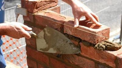 A brick layer builds an extension.