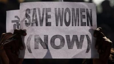 Indian protestors hold a placard as they take part in a rally in front of a statue of Mahatma Gandhi in Lucknow, after the death of a gangrape victim from the Indian capital New Delhi