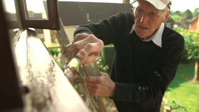 Older man painting window