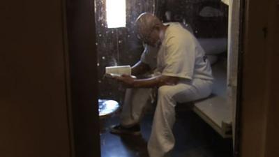 Man reads a book in solitary confinement cell