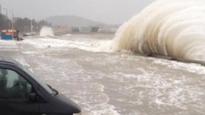 Waves crash over the sea wall at Porth Eirias, Colwyn Bay