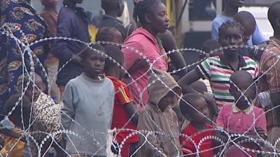 Crowds standing behind razor wire