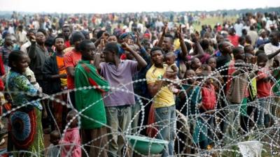 Crowds standing behind razor wire, cheering