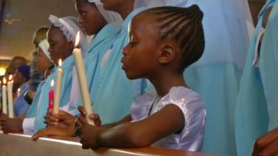 A child holds a lit candle at a memorial service for Nelson Mandela