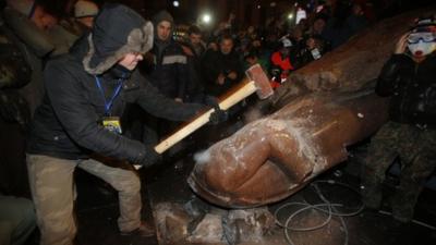 Protesters attacking toppled statue of Lenin