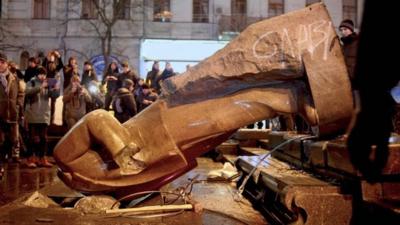 People surround a statue of Soviet state founder Vladimir Lenin, which was toppled by protesters during a rally organized by supporters of EU integration in Kiev