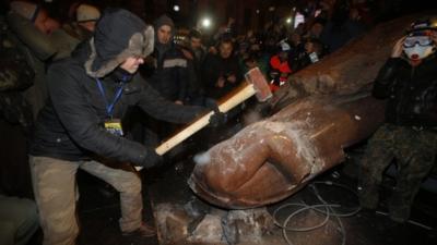 An anti-government protester smashes the statue of Vladimir Lenin with a sledgehammer in Kiev, Ukraine, 8 December 2013