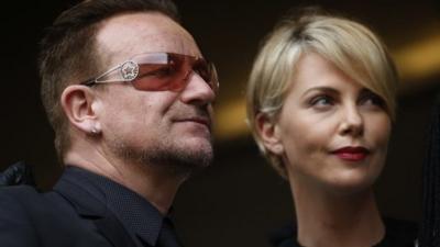 Actress Charlize Theron waits with musician Bono for the memorial service for former South African president Nelson Mandela at the FNB Stadium