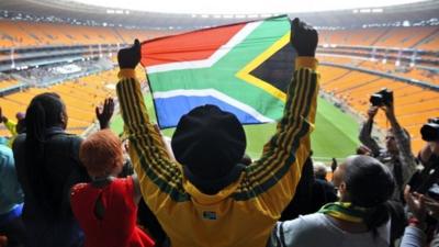 A man holds a South African flag at the Memorial Service for former South African President Nelson Mandela