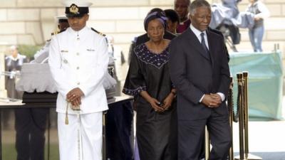 Former South African president Thabo Mbeki (R) walks on after paying his respects at the coffin of former South African President Nelson Mandela as he lies in state at the Union Buildings in Pretoria December 11