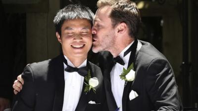 Ivan Hinton, right, gives his partner Chris Teoh a kiss