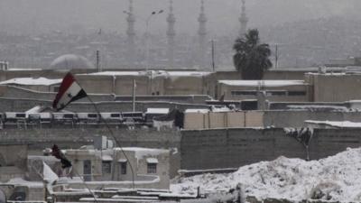 A Syrian national flag is seen on a building covered with snow in the city of Aleppo December 11 ,2013