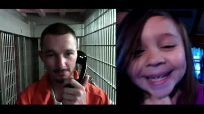 A daughter speaks to her inmate father via video-link in prison