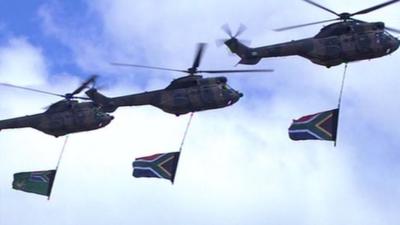 Military helicopters fly over the site at Qunu