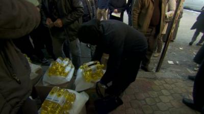 Woman collecting bottles of oil - supplied by the UN