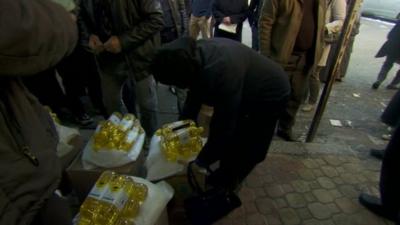 Woman collecting bottles of oil - supplied by the UN